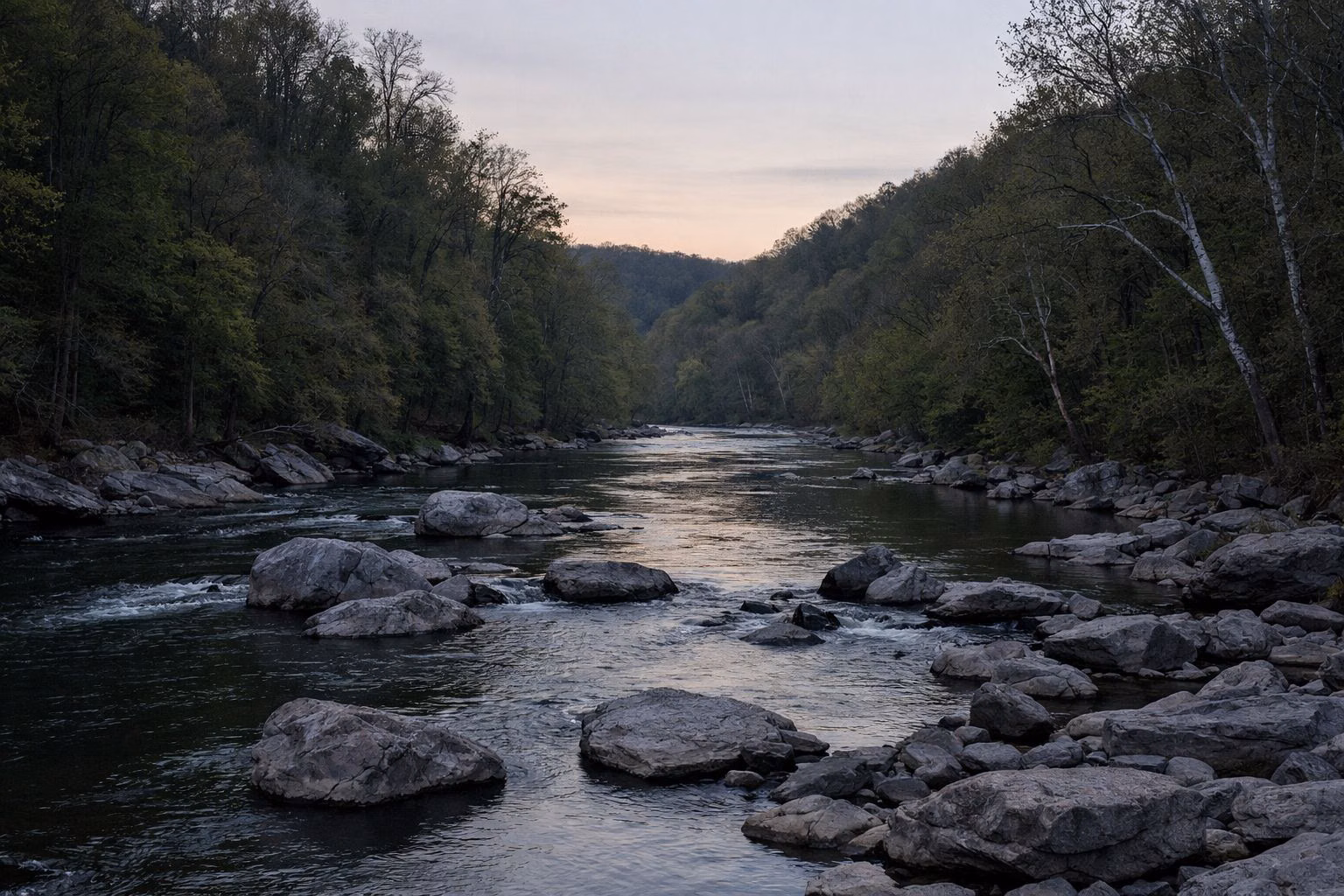 A forested river valley at dusk, soft light on the water, dark wooded ridges
